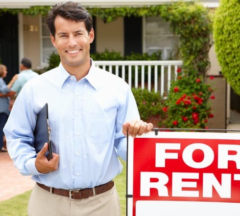 image of a landlord standing infront of a Foley, AL house next to a For Rent sign smitted with his new Landlord Insurance policy